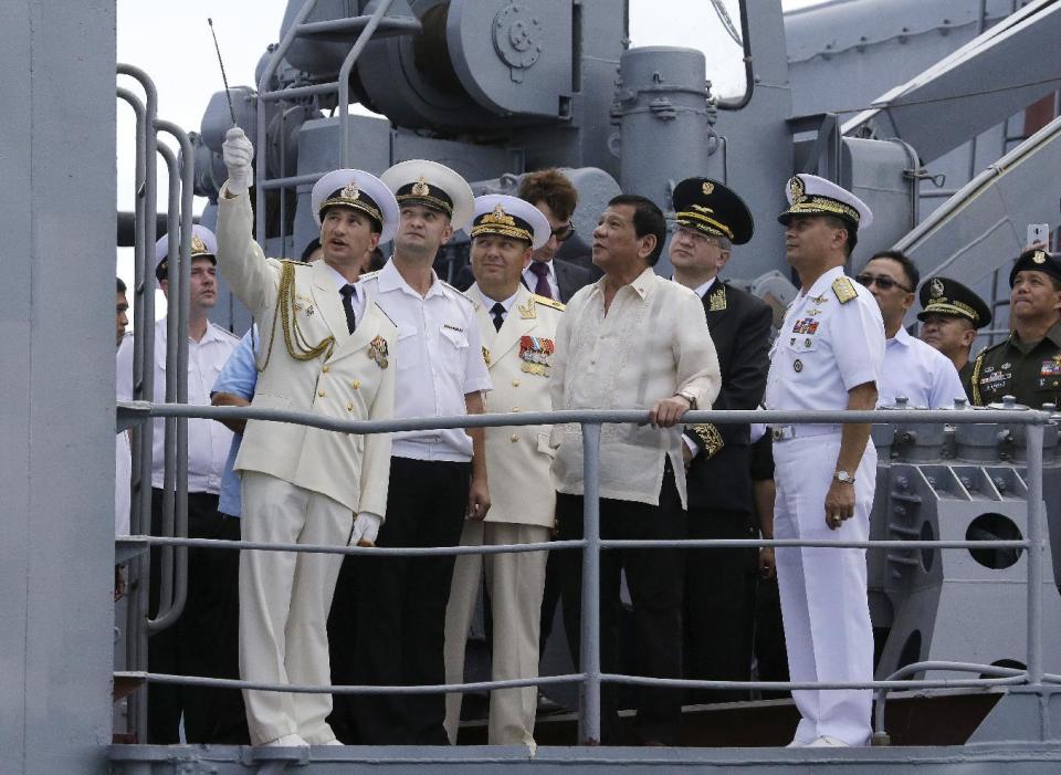 FILE - In this Jan. 6, 2017, file photo, Philippine President Rodrigo Duterte, center, watches as Russian navy officers show the weapons on board the Russian anti-submarine Navy vessel Admiral Tributs in Manila, Philippines. A flurry of goodwill visits by ships and submarines has marked the new year in the South China Sea. In the Philippines, two Russian warships docked in Manila for a five-day visit in a showcase by Moscow to demonstrate what it can offer to a traditional U.S. ally. (AP Photo/Aaron Favila, File)