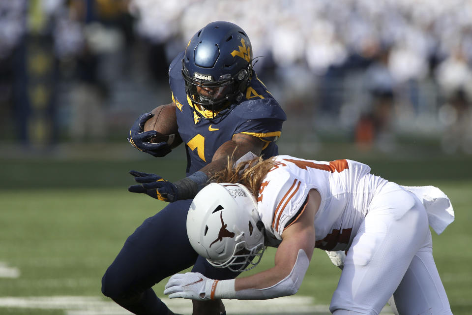 West Virginia running back Leddie Brown (4) is hit by Texas defensive back Brenden Schooler (14) during the second half of an NCAA college football game in Morgantown, W.Va., Saturday, Nov. 20, 2021. (AP Photo/Kathleen Batten)