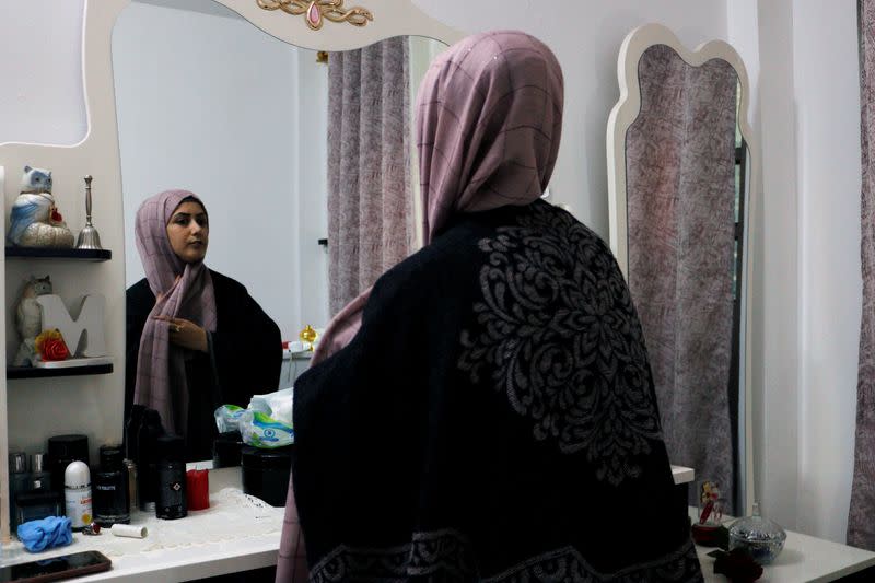 Jassem, 24, an Iraqi nurse arranges her scarf in front of a mirror at home in Baghdad