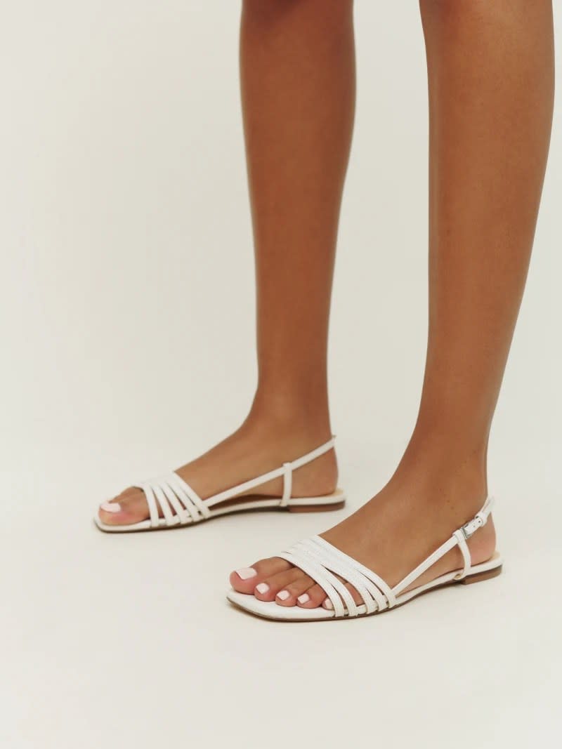 model wearing white open-toe reformation sandals