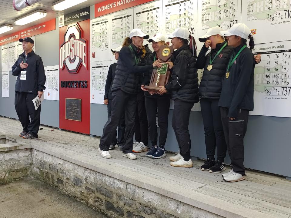 Columbus Academy girls golf coach Maggie Freytag hands senior Angela Hu the Division II state championship trophy Saturday at Ohio State. The Vikings shot 620 as a team to beat runner-up Sugarcreek Garaway by 17 shots.