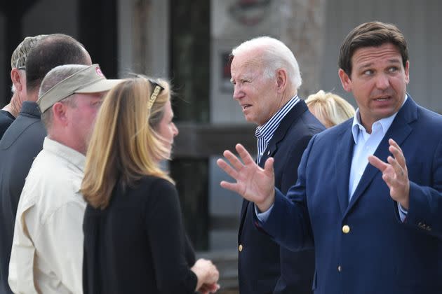 Florida Gov. Ron DeSantis (right) gestures as President Joe Biden (center) speaks with local residents impacted by Hurricane Ian in Fort Myers, Florida, on Wednesday. (Photo: OLIVIER DOULIERY via Getty Images)