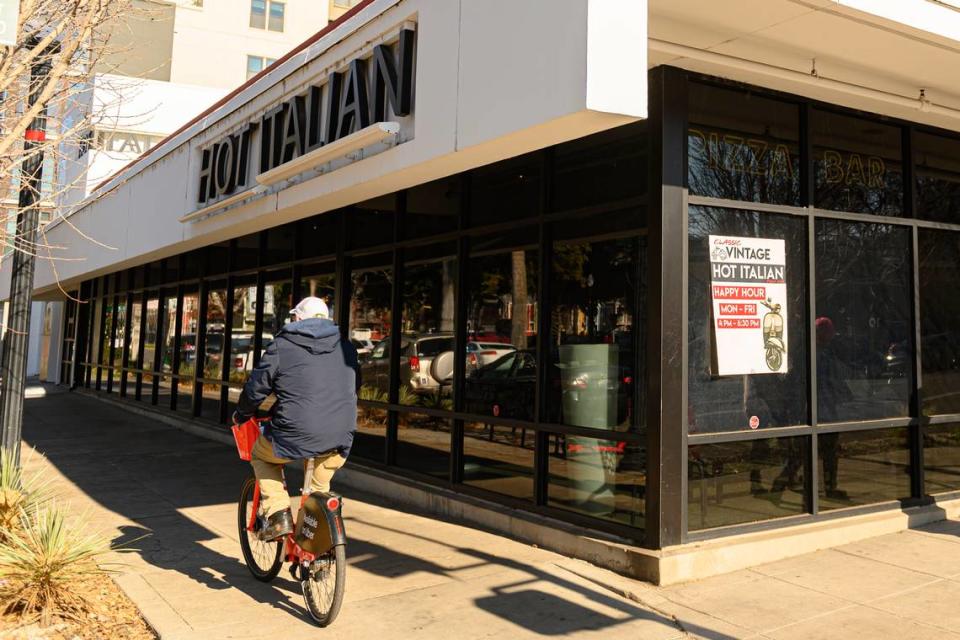 A man rides by Hot Italian in downtown Sacramento in 2019, as patrons inside enjoy a last meal before the restaurant closes its doors permanently.