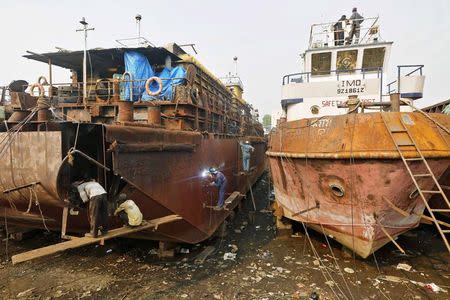 Workers repair a ship at a dry dockyard in Mumbai November 17, 2014. REUTERS/Shailesh Andrade