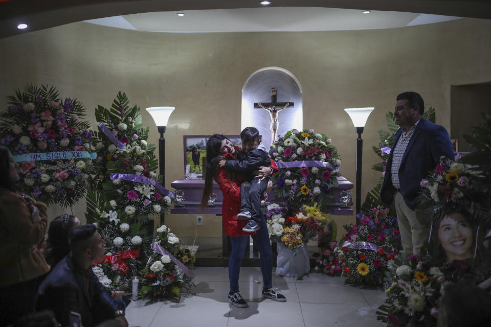 Brenda Valdez holds her son after delivering some words during the wake for her sister Marbella at a funeral home in Tijuana, Mexico, Friday, Feb. 14, 2020. When the law student’s body was found at a garbage dump in Tijuana, the man who was obsessed with her demanded police solve the case, attended her funeral, and a week later was arrested and charged with her murder. The man, identified by Mexican rules only by his first name, Juan, has insisted on his innocence. (AP Photo/Emilio Espejel)