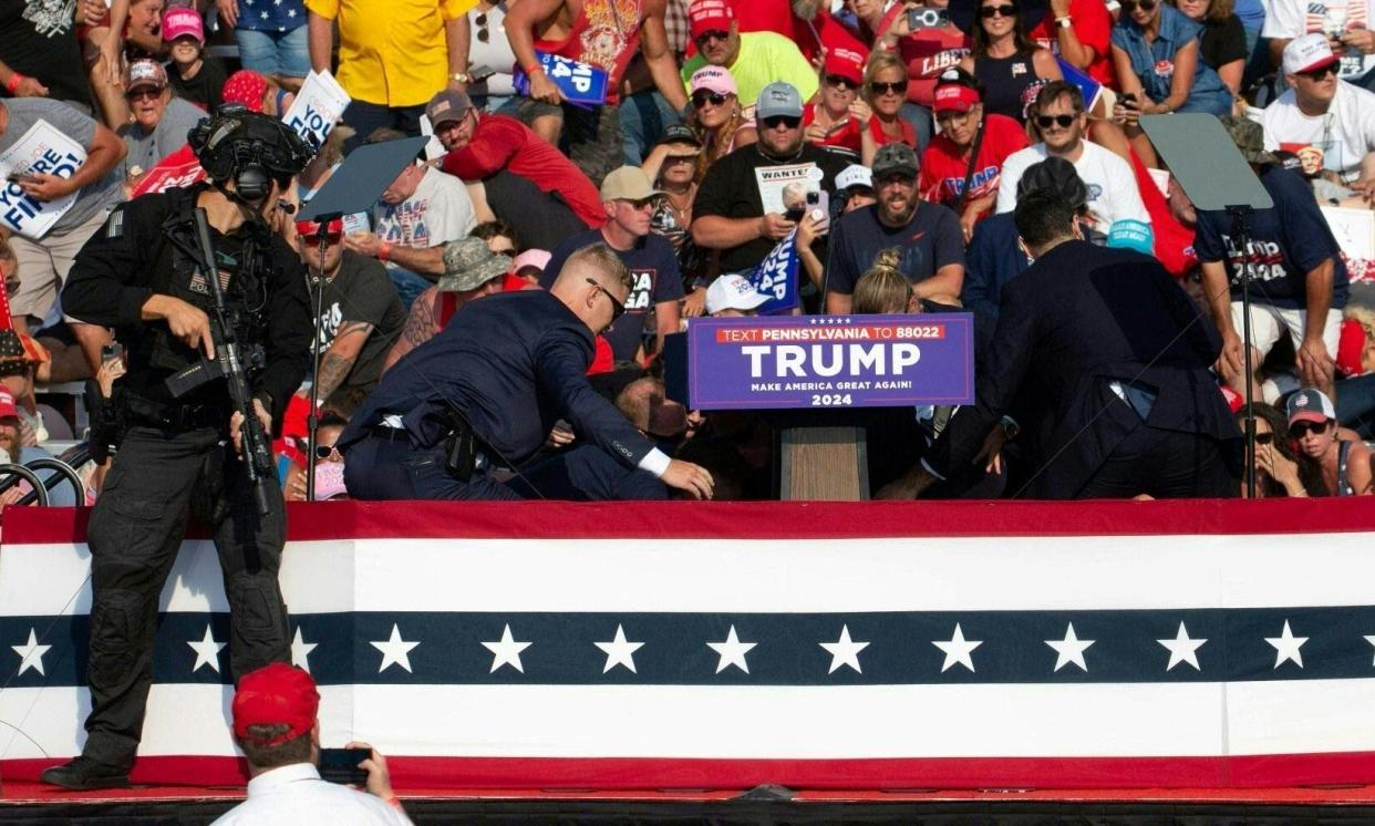 <span>Republican candidate Donald Trump is seen with blood on his face surrounded by Secret Service agents in Butler, Pennsylvania, on 13 July 2024.</span><span>Photograph: Rebecca Droke/AFP/Getty Images</span>