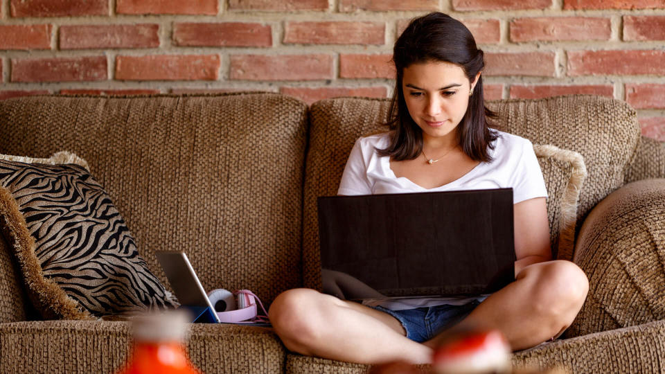 Hispanic young woman working on a laptop computer at home.