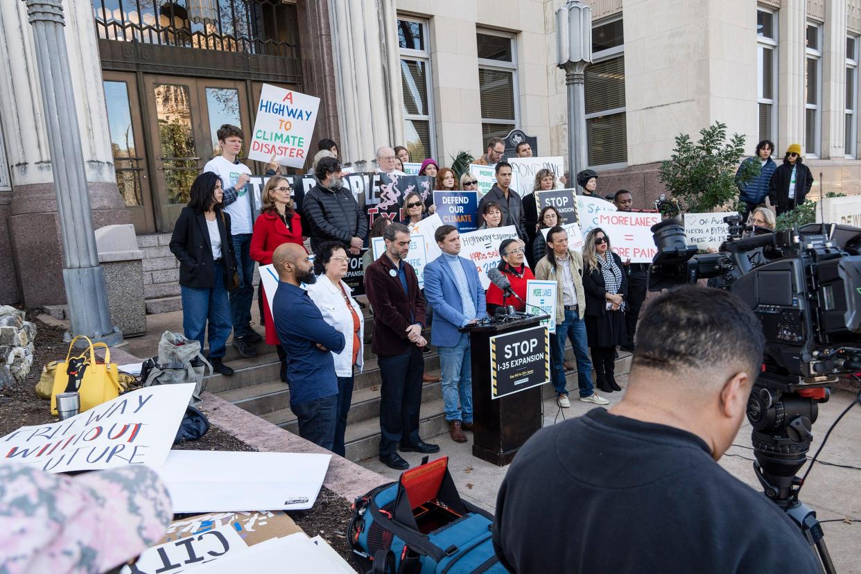 Nearly two dozen people stood on the front steps of TxDOT's headquarters for the news conference. Some held signs saying, "Wider won't work," "A highway to climate disaster" and "More lanes = more traffic."