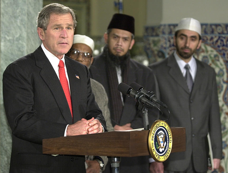 President George W. Bush makes remarks during a visit to the Islamic Center of Washington December 5, 2002, to mark the end of the Muslim holy month of Ramadan. Bush praised the contributions of Muslim-Americans in a bid to deflect criticism of the administration's anti-Iraq campaign. Listening are imams (L to R): Yusef Saleen, Zulkamian Hatta and Mohammad Bashar Arafat. (Photo: Mike Theiler/Reuters)