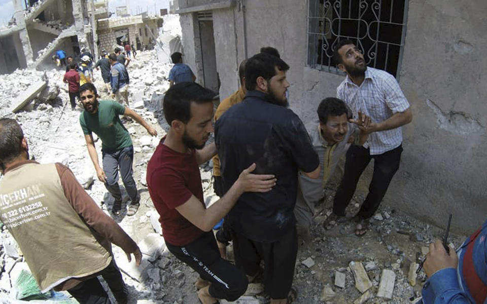 This photo posted and provided by the Syrian Civil Defense White Helmets, which has been authenticated based on its contents and other AP reporting, shows Syrians gathering at the scene where an airstrike by Syrian government forces hit the town of Jabal al-Zawiya in Idlib province, Syria, Saturday, June 15, 2019. Syrian opposition activists say government airstrikes on rebel-held areas in northwestern Syrian and intense fighting claimed the lives dozens of people. (Syrian Civil Defense White Helmets via AP)