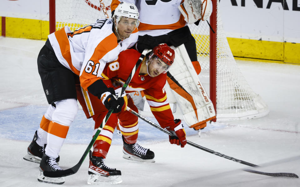 Philadelphia Flyers defenseman Justin Braun, left, checks Calgary Flames forward Andrew Mangiapane during second-period NHL hockey game action in Calgary, Alberta, Monday, Feb. 20, 2023. (Jeff McIntosh/The Canadian Press via AP)