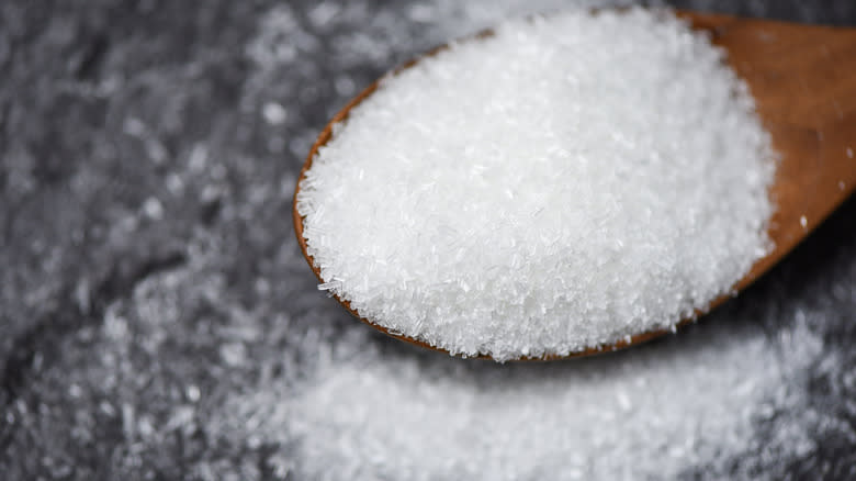 monosodium glutamate on wooden spoon atop grey counter