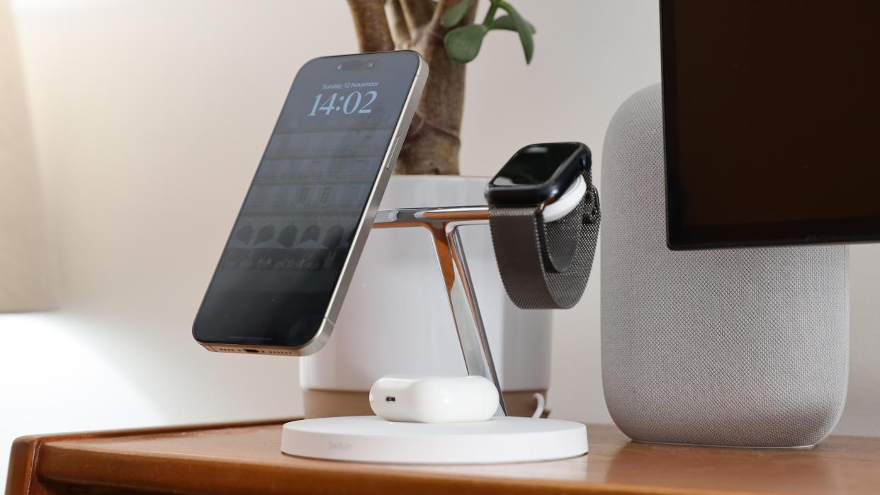  Belkin BoostCharge Pro 3-in-1 Wireless Charger with attached iPhone, AirPods, and Apple Watch on a wooden desk. 