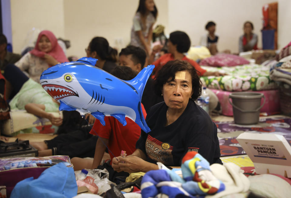 A woman holds a balloon at a temporary shelter for those affected by the flood in Jakarta, Indonesia, Friday, Jan. 3, 2020. Severe flooding in the capital as residents celebrated the new year has killed dozens of people and displaced hundreds of thousands others. (AP Photo/Dita Alangkara)