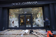 A passerby photographs a smashed Dolce and Gabbana store window in the SoHo neighbourhood of New York, Monday, June 1, 2020. Protesters broke into the store Sunday night in reaction to George Floyd's death while in police custody on May 25 in Minneapolis. (AP Photo/Mark Lennihan)