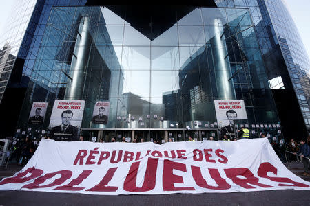 Environmental activists block the entrance of the French bank Societe Generale headquarters during a "civil disobedience action" to urge world leaders to act against climate change, in La Defense near Paris, France, April 19, 2019. The slogan reads " Macron, President of polluters". REUTERS/Benoit Tessier