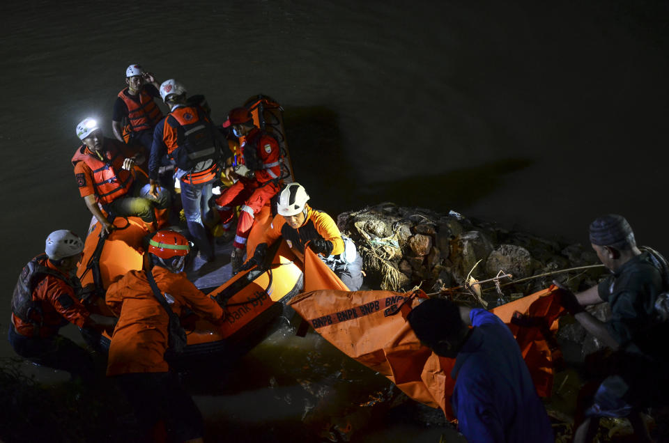 Rescuers remove a body from the water during a search for the victims of drowning in a river in Ciamis, West Java, Indonesia, Friday, Oct. 15, 2021. A number of students drowned during a school outing for a river cleanup on Friday evening in Indonesia's West Java Province. (AP Photo/Yopi Andrias)