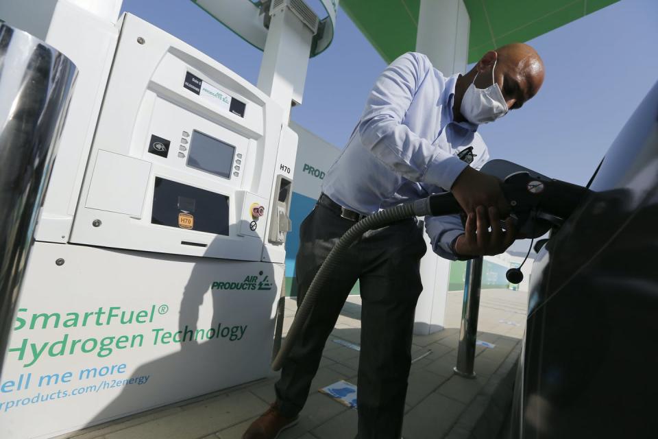 A man filling a vehicle fuel tank from a hydrogen pump