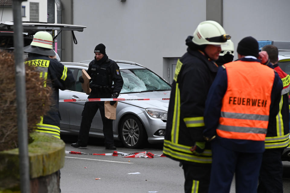 Einsatzkräfte an dem Auto, das zuvor in den Umzug gerast war (Bild: Uwe Zucchi/dpa)