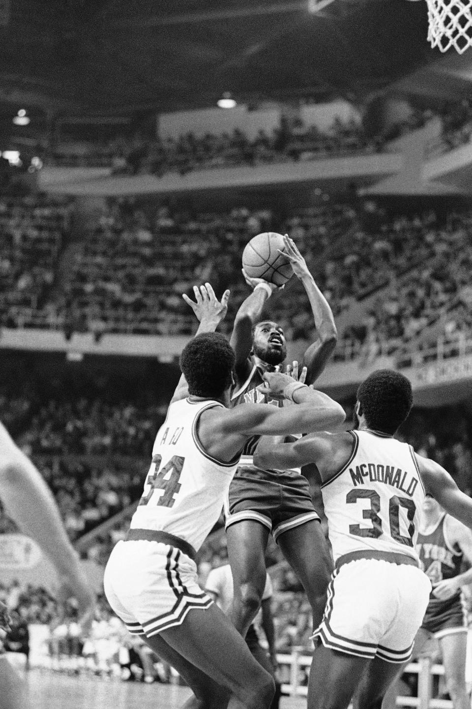 New York Knicksí Earl Monroe lays up a shot over Boston Celticsí Jim Ard (34), and Glenn McDonald (30) in the second period of their National Basketball Association game at Boston Garden, Friday, Nov. 22, 1975. Boston won the game 110 to 101. (AP Photo)