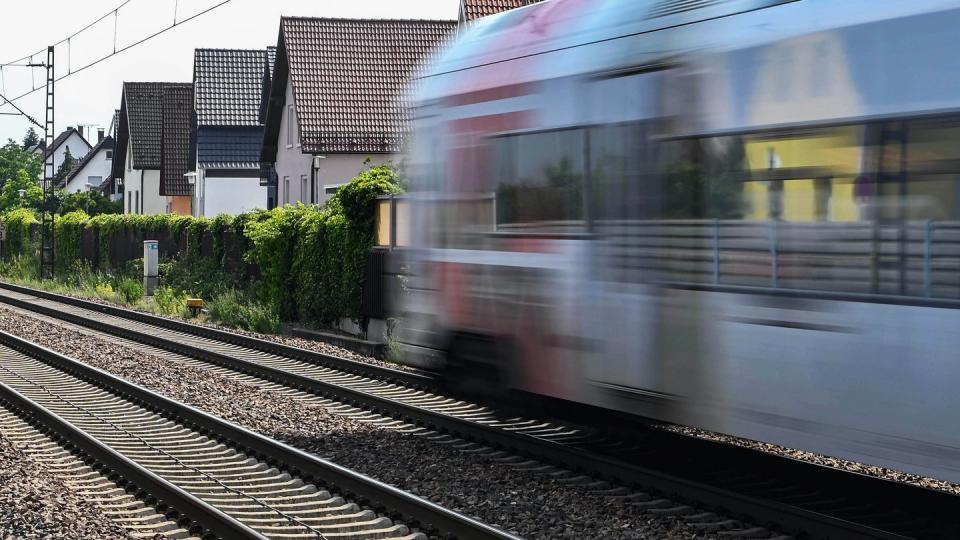 Auf der Bahnstrecke Karlsruhe-Mannheim fährt ein Zug an Häusern vorbei.