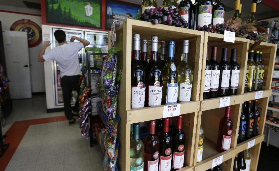 In this Thursday, May 23, 2013 photo, shelves of wine line the entrance to a gas station as a customer looks into a cooler, in Blaine, Wash. In April 2013, in its 2014 fiscal year budget proposal, the Department of Homeland Security requested permission to study a fee at the nation's land border crossings. The request has sparked wide opposition among members of Congress from northern states, who vowed to stop it. A fee, they say, would hurt communities on the border that rely on people, goods and money moving between the U.S. and Canada. (AP Photo/Elaine Thompson)