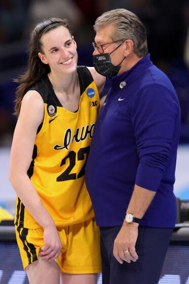 UConn coach Geno Auriemma wears a mask while speaking with Iowa's Caitlin Clark