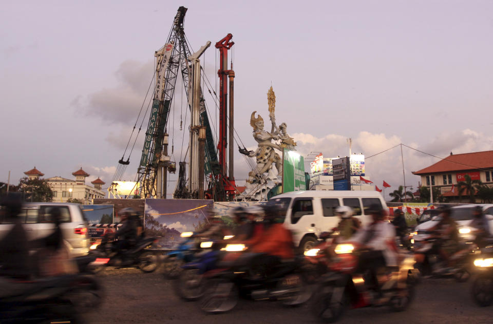 This Aug. 25, 2012 photo shows cranes next to a traditional Balinese statue called Dewa Ruci at the site of road construction in Kuta Bali, Indonesia. It can be hard to find Bali's serenity and beauty amid the villas with infinity pools and ads for Italian restaurants. But the rapidly developing island's simple pleasures still exist, in deserted beaches, simple meals of fried rice and coconut juice, and scenes of rural life. (AP Photo/Firdia Lisnawati)