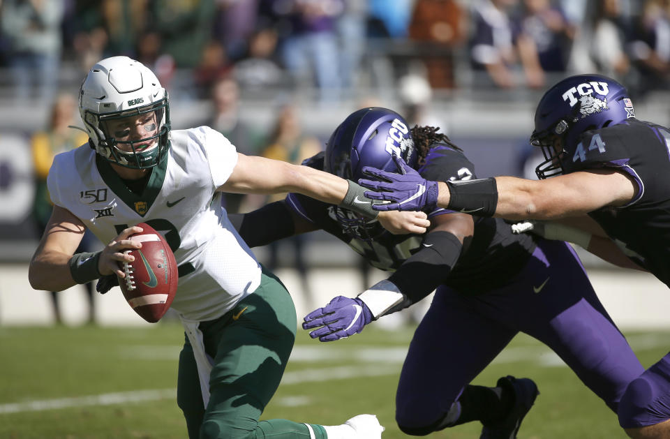 Baylor quarterback Charlie Brewer (12) tries to avoid the rush of TCU defensive ends Ochaun Mathis (32) and Colt Ellison (44) during the first half of an NCAA college football game, Saturday, Nov. 9, 2019, in Fort Worth, Texas. (AP Photo/Ron Jenkins)