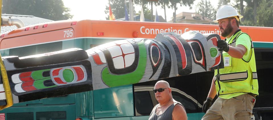 Bill Martin Jr., back, looks on as Port Orchard Public Works’s John Harmon helps guide the totem pole as it is lifted from a trailer to be put back into its position at the end of Sidney Ave. at the waterfront in Port Orchard on Wednesday, Aug. 30, 2023. Martin’s grandfather - Frank Smith. - was the original carver of the pole.