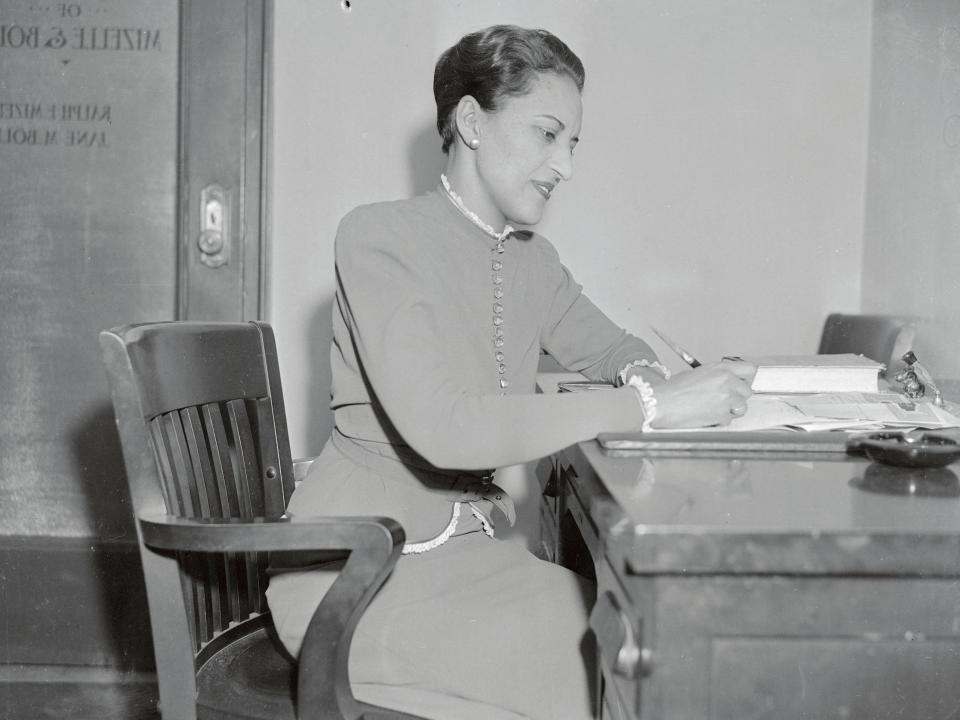 Black and white photo of Jane Bolin writing on paper at a desk.