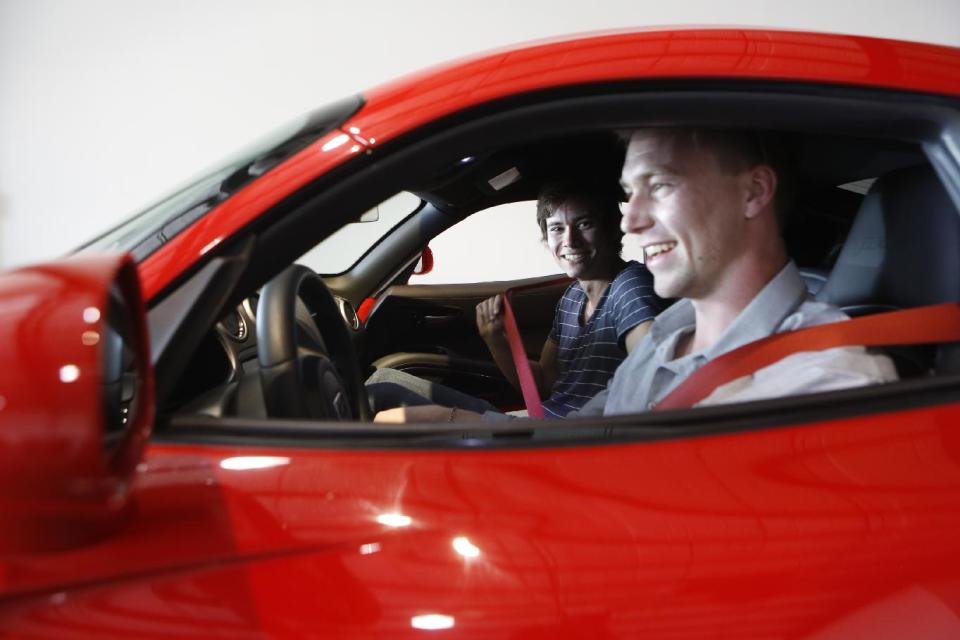 In this Wednesday, March, 26, 2014 photo, Douglas Sawyer, 23, right, and Michael Clark, 22, left, both from Chicago rent a 2013 Dodge Viper at the Enterprise Exotic Car Collection showroom near Los Angeles International Airport. (AP Photo/Damian Dovarganes)