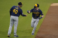 Milwaukee Brewers' Billy McKinney, right, reacts with third base coach Jason Lane (40) after hitting a home run during the third inning of a baseball game against the San Diego Padres, Tuesday, April 20, 2021, in San Diego. (AP Photo/Gregory Bull)