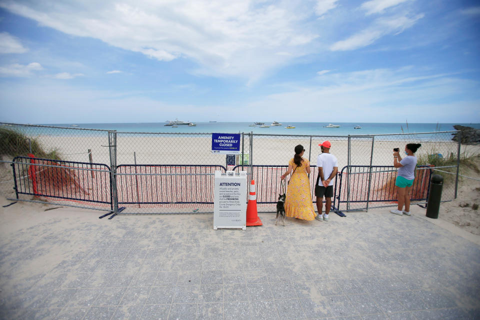 People look through fencing next to signage indicating that the beach is temporarily closed in South Pointe park on July 4, 2020, in the South Beach neighborhood of Miami Beach. / Credit: Cliff Hawkins / Getty