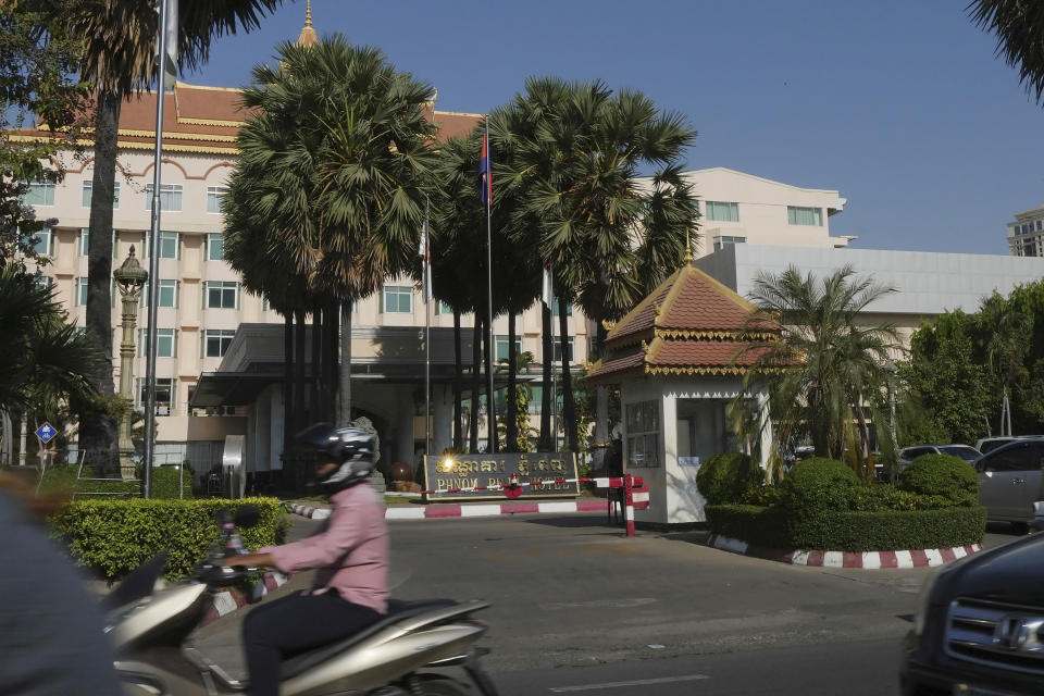 People drive their vehicles past a main entrance of Phnom Penh Hotel in Phnom Penh, Cambodia, Tuesday, April 30, 2024. The European Union and United Nations abruptly rescheduled the launch of an anti-human trafficking program this week after being confronted with questions on the choice of venue: a Phnom Penh hotel owned by a Cambodian tycoon who has another property that has been used by human traffickers. (AP Photo/Heng Sinith)