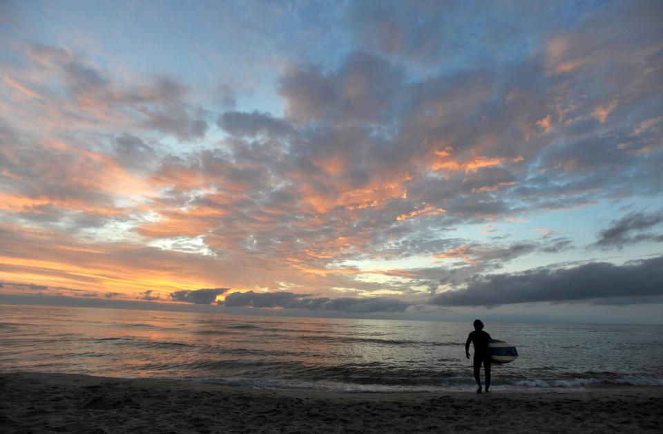 A surfer heads out to sea for his daily sunrise surf along the Cape Cod National Seashore at Coast Guard Beach in Eastham in August 2011.