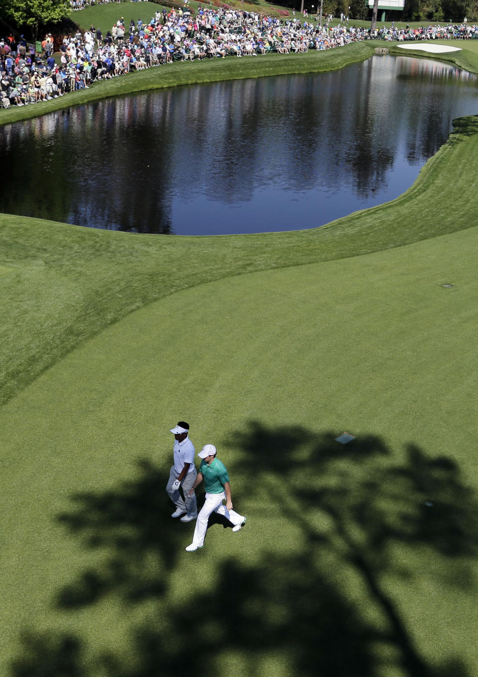 Thongchai Jaidee, left, of Thailand, walks on the 16th fairway with Rory McIlroy, of Northern Ireland, during a practice round for the Masters golf tournament Wednesday, April 9, 2014, in Augusta, Ga. (AP Photo/David J. Phillip)