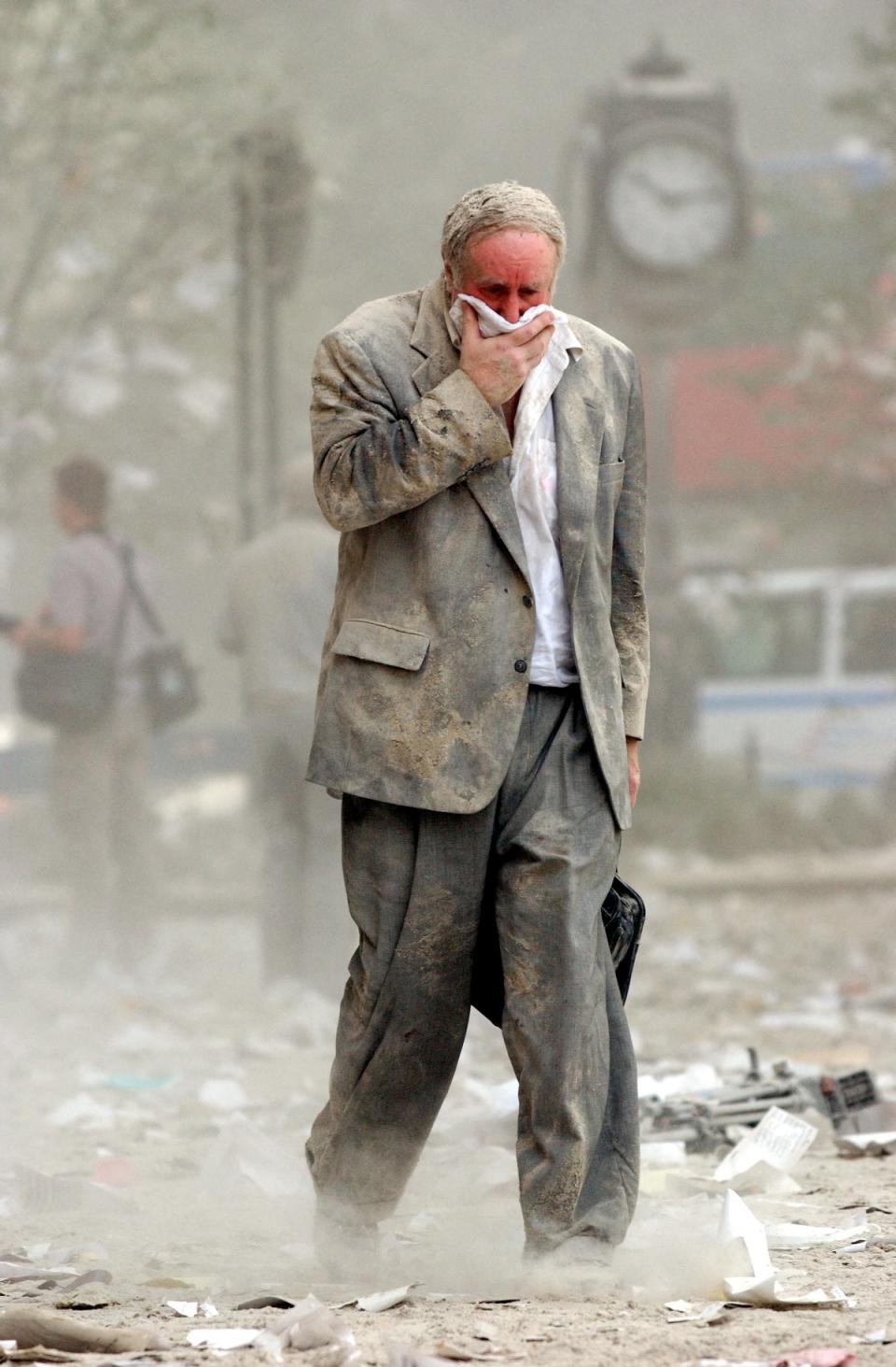 Survivor Edward Fine, who was on the 79th floor of the North Tower when it was struck, covers his mouth as he walks through the debris (AFP/Getty)