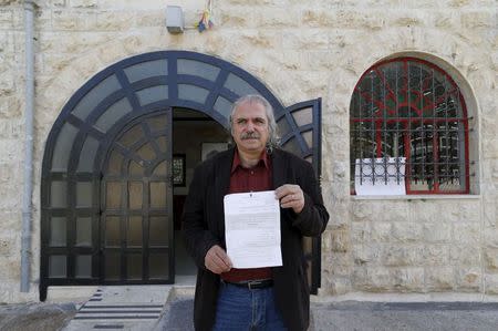 Amer Khalil, director of the Palestinian National Theatre, known as "Al Hakawati" (The Storyteller), holds a court order, as he poses for a picture outside the theatre, in the predominantly Arab neighbourhood of Sheikh Jarrah in East Jerusalem November 27, 2015. REUTERS/Ammar Awad