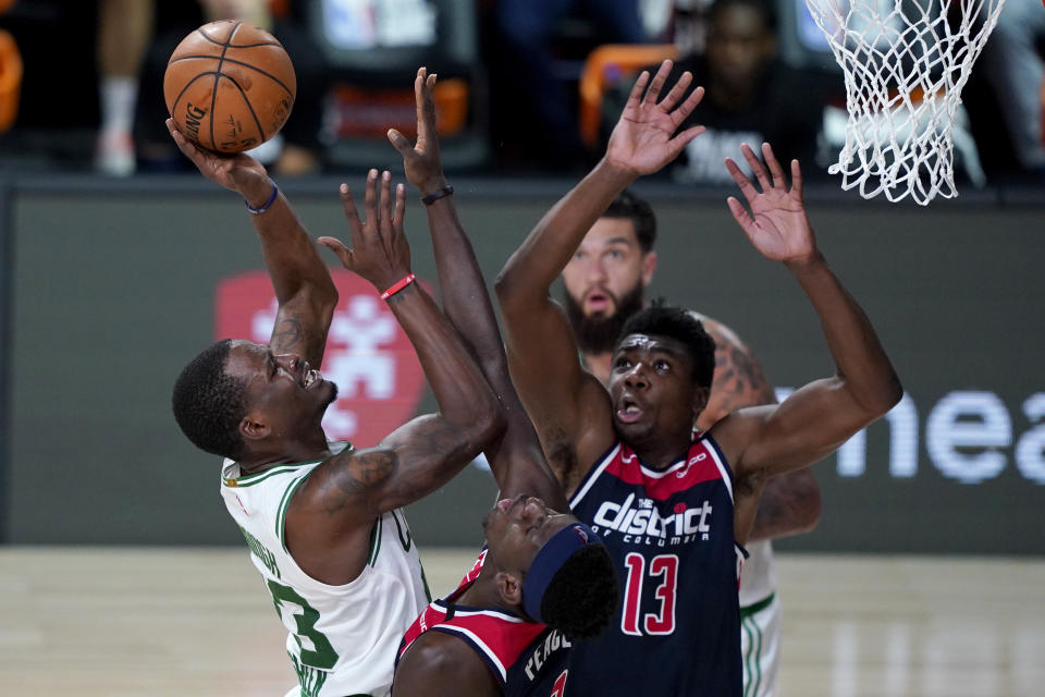 Boston Celtics' Javonte Green, left, heads to the basket past Washington Wizards' Isaac Bonga and Thomas Bryant (13) during the second half of an NBA basketball game Thursday, Aug. 13, 2020 in Lake Buena Vista, Fla. (AP Photo/Ashley Landis, Pool)