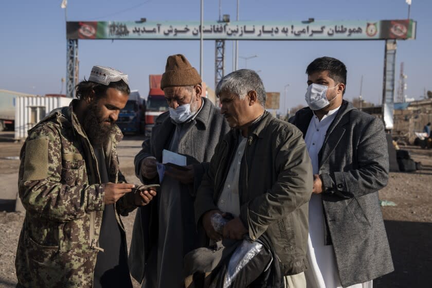 A Taliban fighter checks passports at the Afghanistan-Iran border crossing of Islam Qala, on Wednesday, Nov. 24, 2021. Afghans are streaming across the border into Iran, driven by desperation after the near collapse of their country's economy following the Taliban's takeover in mid-August. In the past three months, more than 300,000 people have crossed illegally into Iran, according to the Norwegian Refugee Council, and more are coming at the rate of 4,000 to 5,000 a day. (AP Photo/Petros Giannakouris)