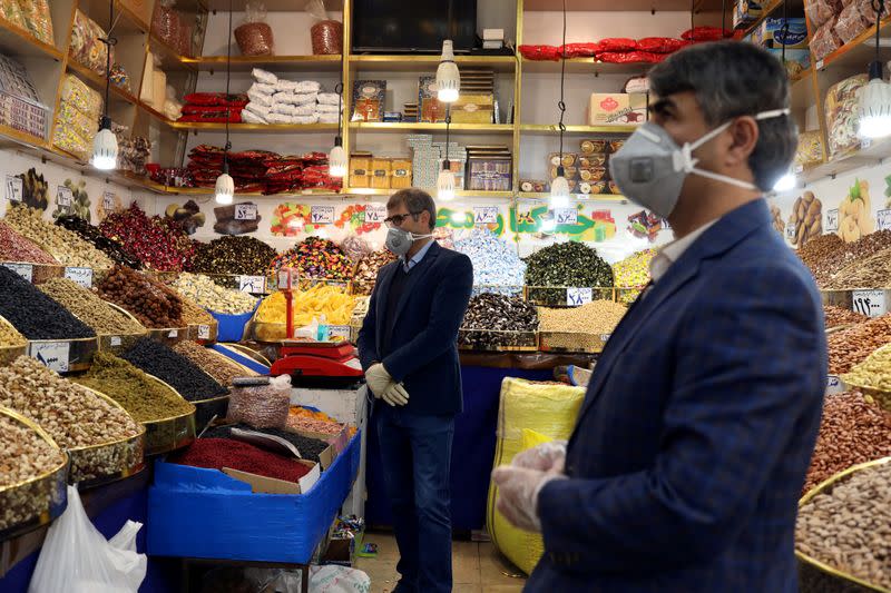 FILE PHOTO: Men wear protective face masks and gloves, following the outbreak of coronavirus, as they are seen in a nuts shop in Tehran