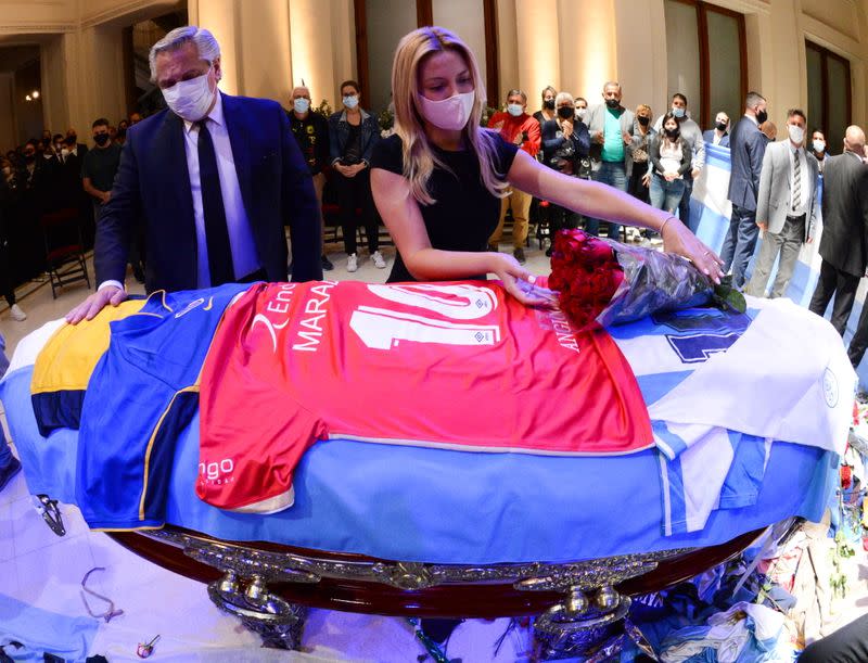 Argentina's first lady Fabiola Yanez places flowers on the casket of soccer legend Diego Maradona as Argentina's President Alberto Fernandez looks on, at the presidential palace Casa Rosada, in Buenos Aires