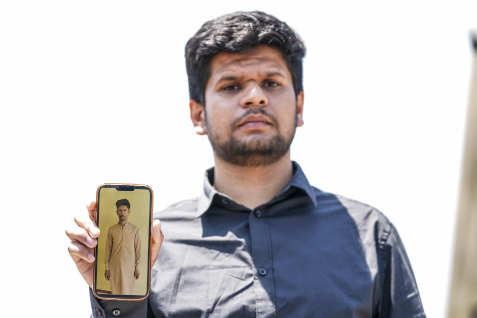 Zohaib Shamraiz holds up a photograph of his missing uncle, 40 year old Nadeem Muhamm, outside a migrant camp in Malakasa north of Athens, on Monday, June 19, 2023. Hundreds of migrants are believed to be missing after a fishing trawler sank off southern Greece last week. (AP Photo/Petros Giannakouris)