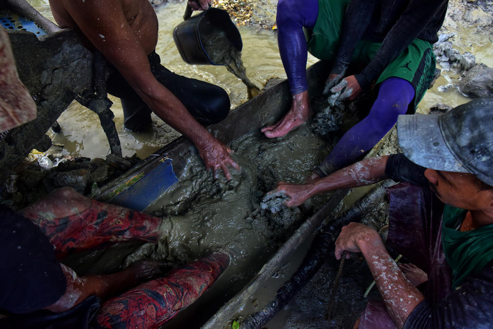 Miners washing mud with hands and feet