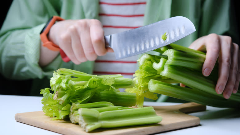 Hands cutting celery on table