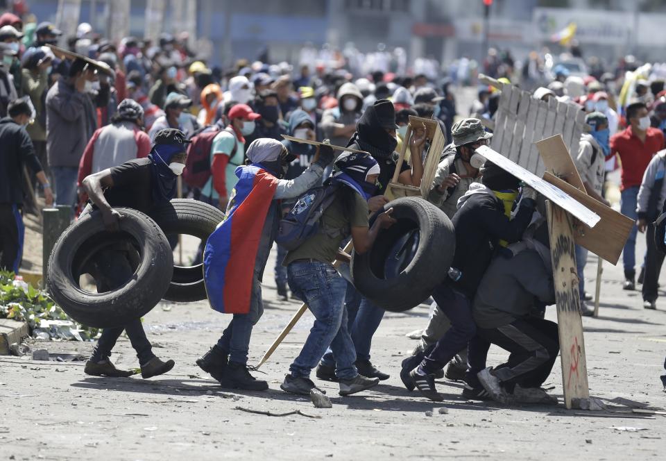 Anti-government demonstrator carry tires to set up a barricade during clashes with police in Quito, Ecuador, Saturday, Oct. 12, 2019. Protests, which began when President Lenin Moreno's decision to cut subsidies led to a sharp increase in fuel prices, have persisted for days. (AP Photo/Fernando Vergara)