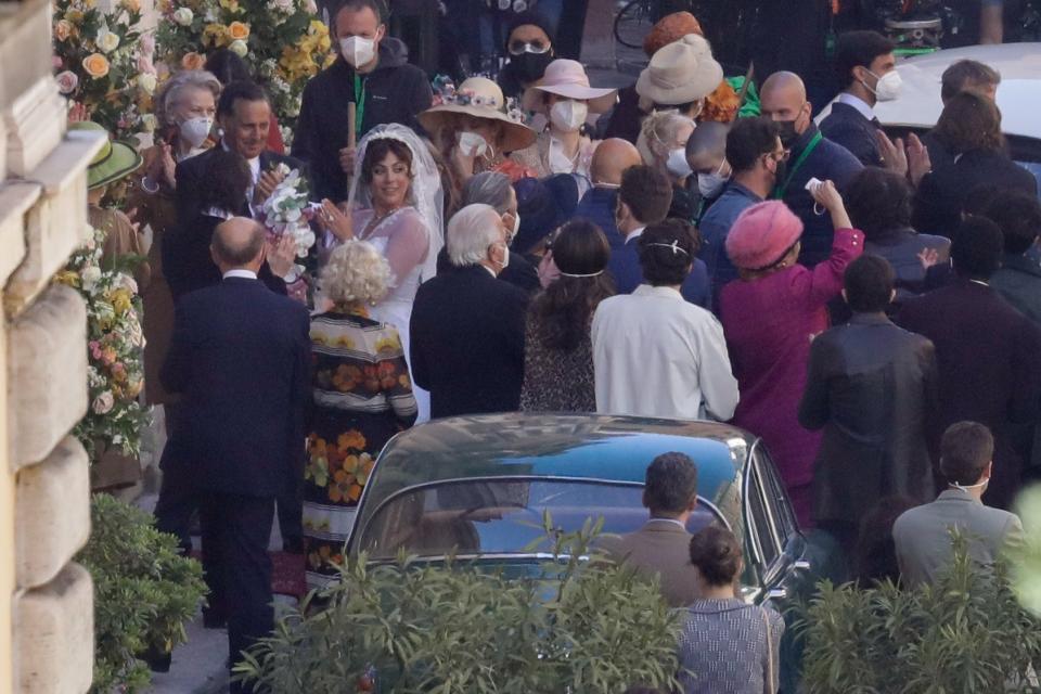 Lady Gaga, wearing a wedding dress in background left, plays Maurizio Gucci's former wife Patrizia Reggiani during the shooting of a movie by Ridley Scott, based on the story of the murder of Maurizio Gucci in 1995, in Rome, Thursday, April 8, 2021. (AP Photo/Andrew Medichini)