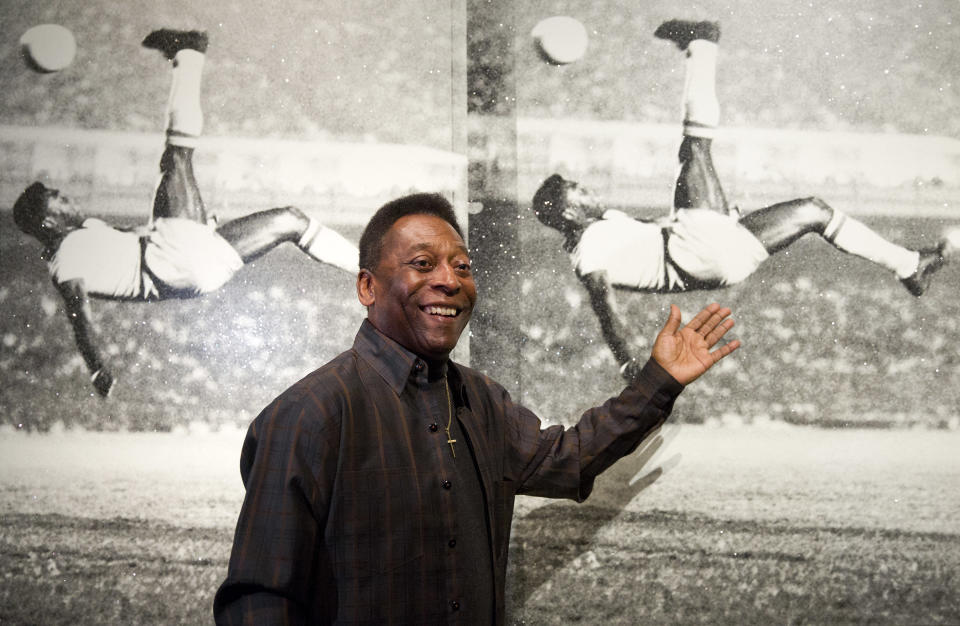 La leyenda del futbol, Pelé, posa frente a la obra Pele, Bicycle Kick del artista Russell Young, previo a una exhibición en retrospectiva de su carrera en 2015 (Foto: Justin TALLIS / AFP) (Photo by JUSTIN TALLIS/AFP vía Getty Images).