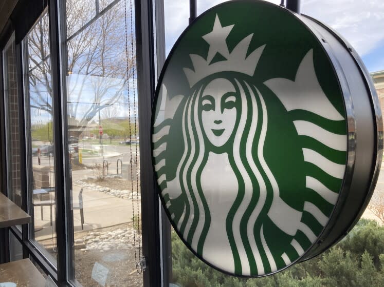 A sign bearing the corporate logo hangs in the window of a Starbucks open only to take-away customers in this photograph taken Monday, April 26, 2021, in southeast Denver. Starbucks is no longer requiring its U.S. workers to be vaccinated against COVID-19, reversing a policy it announced earlier this month. The Seattle coffee giant says, Wednesday, Jan. 19, 2022, it's responding to last week's ruling by the U.S. Supreme Court. (AP Photo/David Zalubowski)